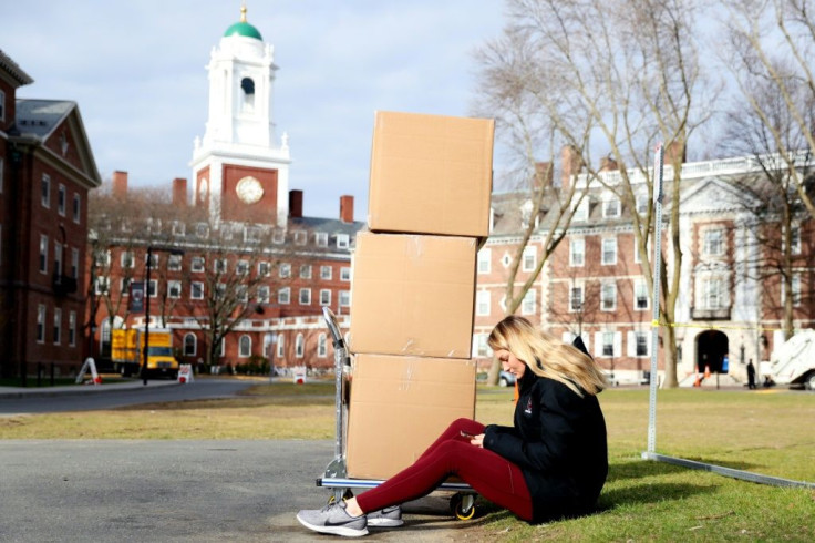 A Harvard student sits with her belongings before returning home on March 12, 2020, as students left campus due to the coronavirus pandemic