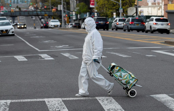 A woman wearing a hazmat suit and googles pulls her grocery cart through New York City on April 20, 2020