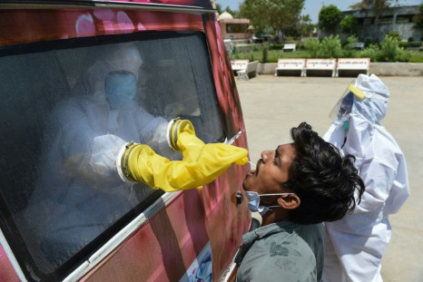 A health official uses a swab to collect a sample from a man for COVID-19 testing at a mobile testing van near  Ahmedabad, India