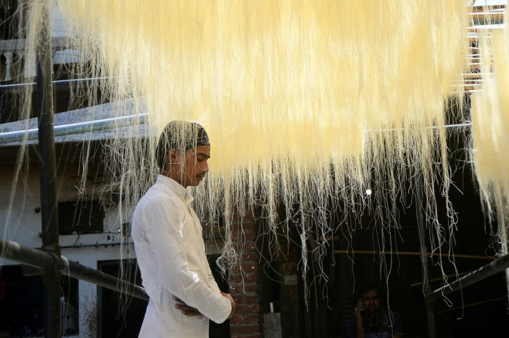 A man prays under vermicelli used to make Ramadan sweets at a factory in Allahabad in India