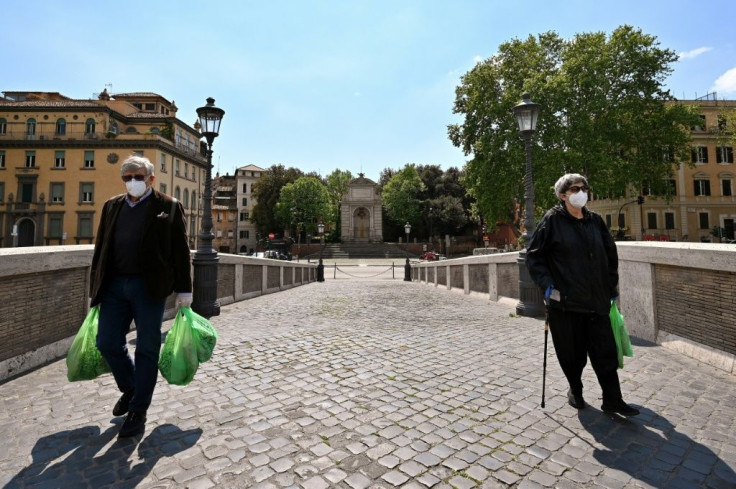 People wearing face masks carry their groceries across the Ponte Sisto bridge on April 24, 2020 in Rome, during the country's lockdown aimed at stopping the spread of the COVID-19 pandemic, caused by the novel coronavirus