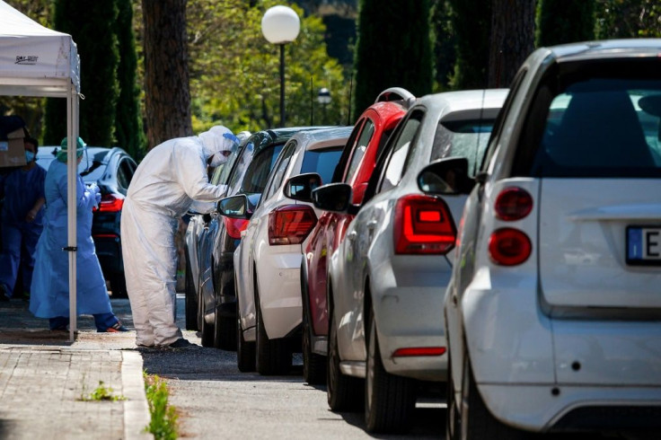 A medical worker performs swabs as drivers line up at a drive-through testing facility for COVID-19 on April 24, 2020 in Rome