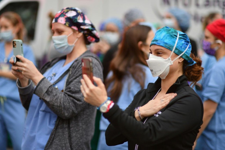 Healthcare workers take video as people cheer to show their gratitude to medical staff outside NYU Langone Health hospital on April 23