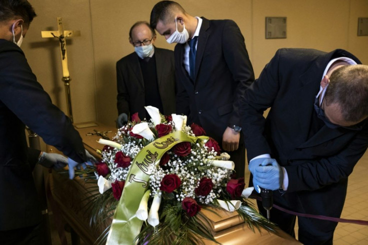 Giampiero Palmero, (2nd L) owner of a funeral home in Revello, supervises his employees as they prepare the coffin of a COVID-19 victim before a funeral service in northern Italy with very limited family contact