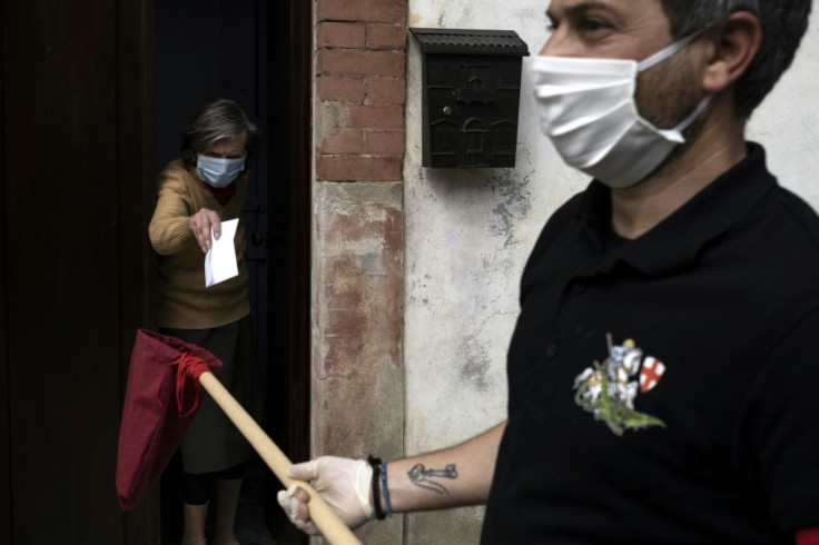 A woman donates money after receiving bread during the feast of San Giorgio in Caresana, northern Italy