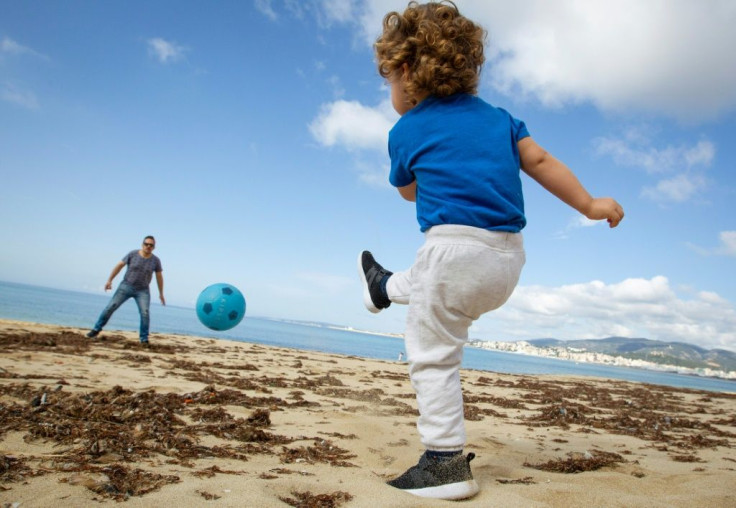 A child plays footbal with his father at Can Pere Antoni Beach in Palma de Mallorca, Spain