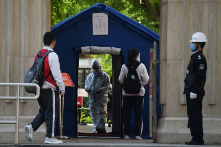 An official in a hazmat suit greets students returning to classes as schools re-open in Beijing