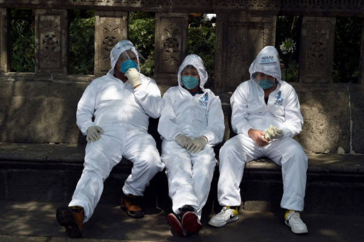 Health workers rest after disinfecting the Angel de la Independencia monument at the Reforma Avenue in Mexico City