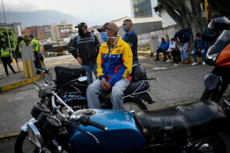 A biker waits to fill up his motorcycle fuel tank near a gas station in Caracas