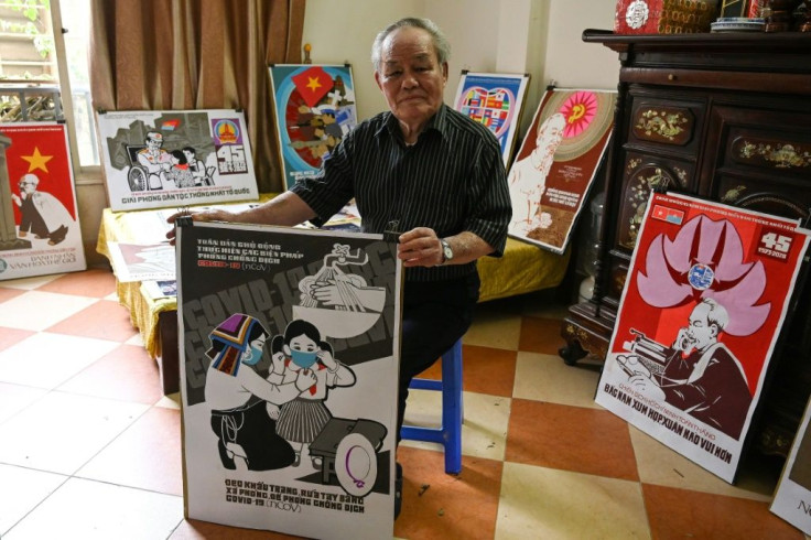 Vietnamese painter Tran Duy Truc poses with the stylised propaganda-art poster he created for the campaign to prevent the spread of coronavirus