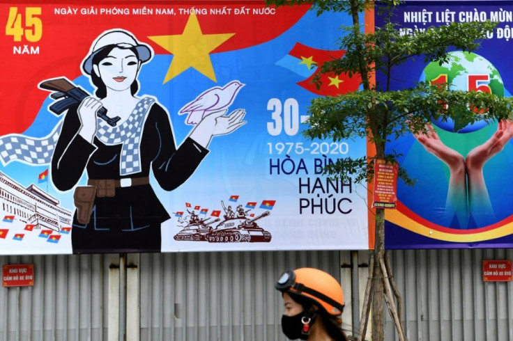 A woman walks next to a hoarding marking the 45th anniversary of the fall of Saigon, in Hanoi