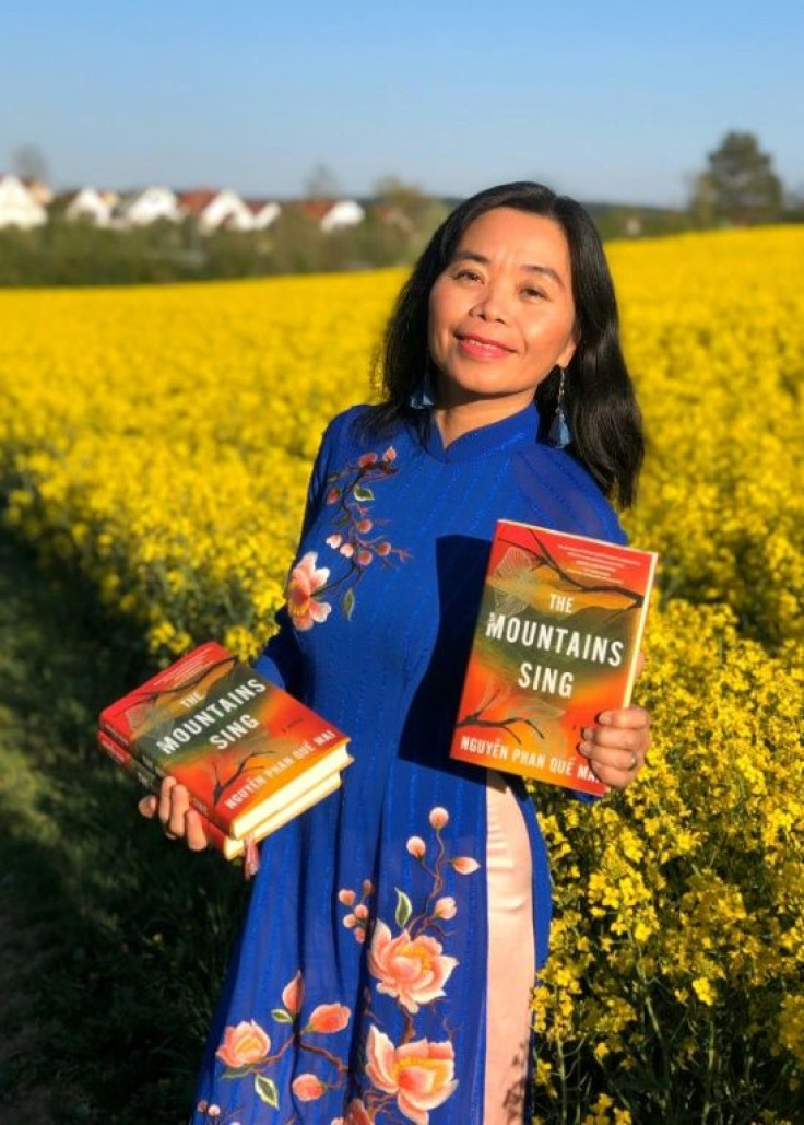 Vietnamese author Nguyen Phan Que Mai holds copies of her novel "The Mountains Sing"