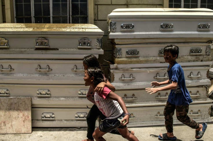 Children run past used caskets at a crematorium facility in Manila