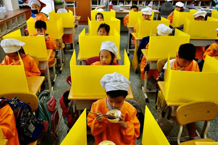 Students in Taipei eat their lunch on desks with plastic partitions