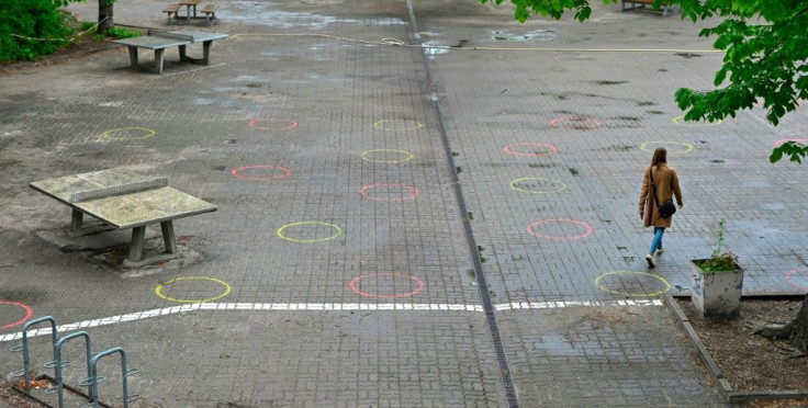 A woman walks in the schoolyard of an elementary school in Berlin where circles have been painted on the ground to mark the recommended distance, in preparation of the return of some pupils from early May 2020