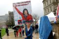 A protestor with a sign depicting Governor Gretchen Whitmer as Adolph Hitler is seen outside the Michigan state capitol in Lansing on April 30, 2020