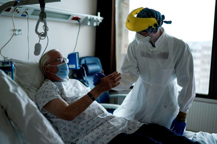 A physiotherapist gives a high five to a patient at the "middle care" unit for the COVID-19 infected patients at the Erasme Hospital in Brussels