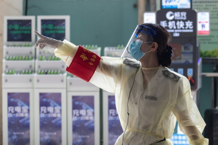 A staff member wearing a face shield points instructions at a bus station in Wuhan in China's central Hubei province