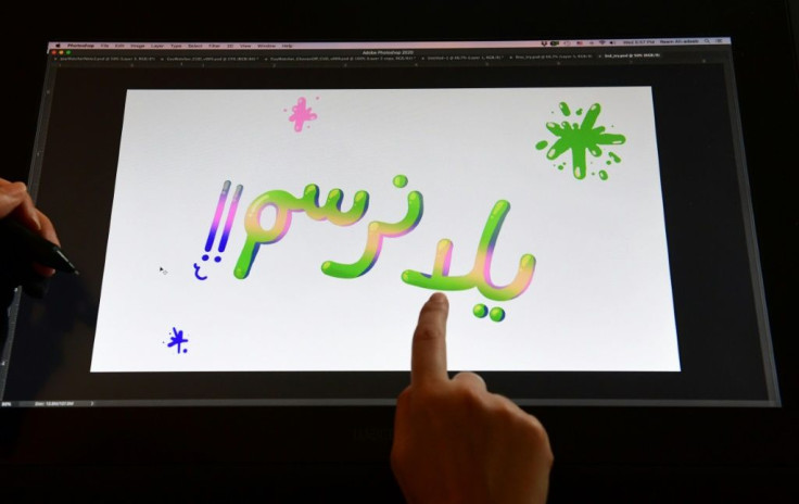 Artist Reem Ali Adeeb points to the words "Let's Draw" in Arabic script while working in her studio apartment in Los Angeles, California on April 29, 2020, where she is developing online tutorials in Arabic for children about art