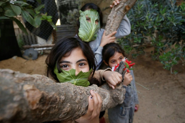 Palestinian children pose with makeshifts masks made of cabbage while cooking at home with their family in Beit Lahia in the northern Gaza Strip on April 16, 2020 amid the coronavirus COVID-19 pandemic.