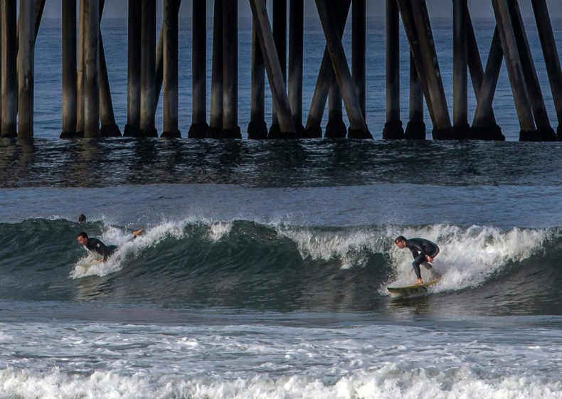 Surfers catch a wave in Huntington Beach, California on May 2