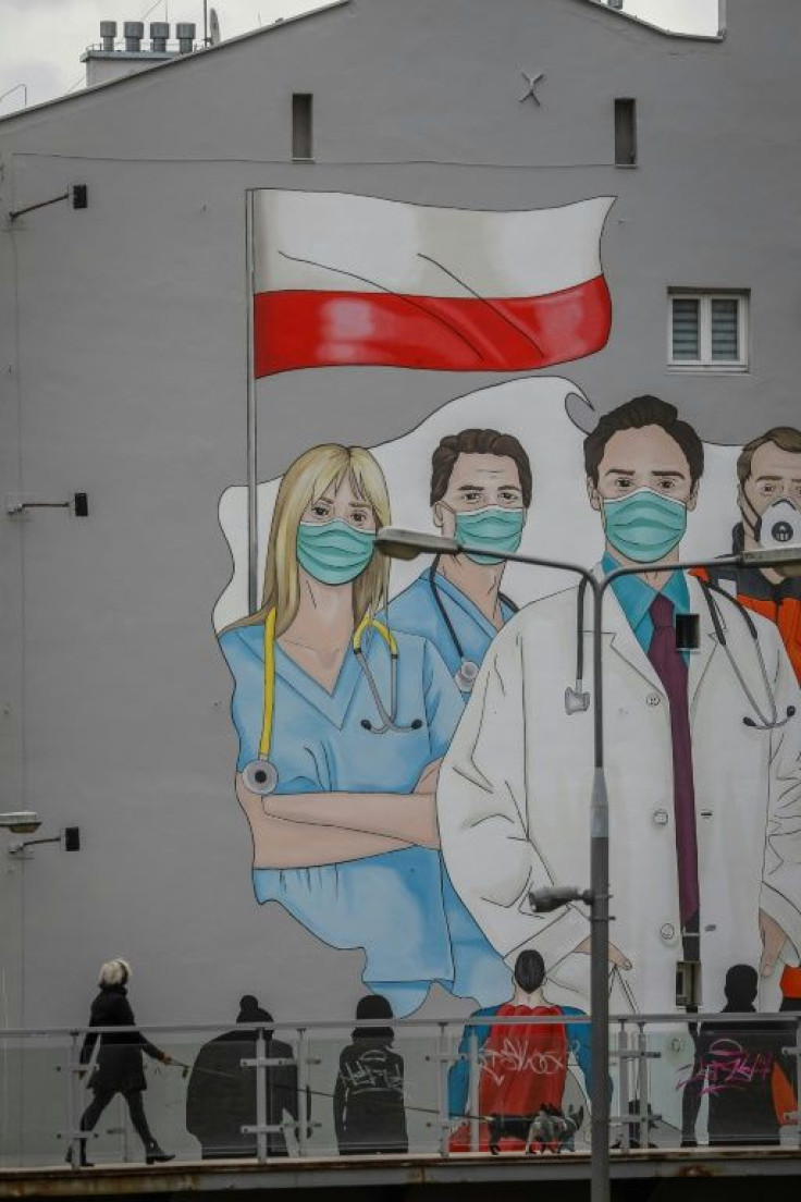 A woman walks past a mural paying tribute to the sacrifice of doctors in Poland, which sent a medical team to the United States to help its ally battle the COVID-19 coronavirus