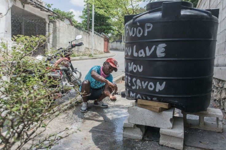 A motorcycle taxi driver washes his hands at one of the many hand washing kiosks set up in Port-au-Prince's Nerette district
