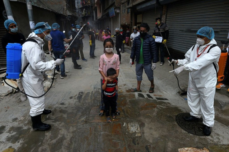 Health workers wearing protective suits spray disinfectant on children during a government-imposed nationwide lockdown in Kathmandu, Nepal