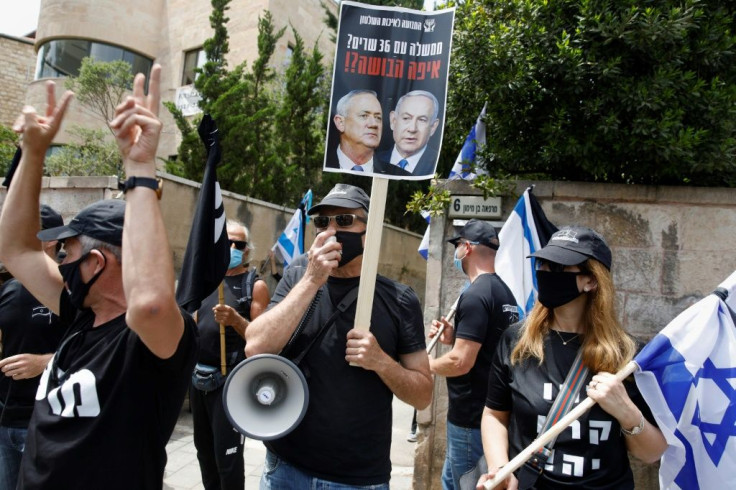 An Israeli protester holds a placard with a picture of Prime Minister Benjamin Netanyahu and his former rival Benny Gantz in Jerusalem