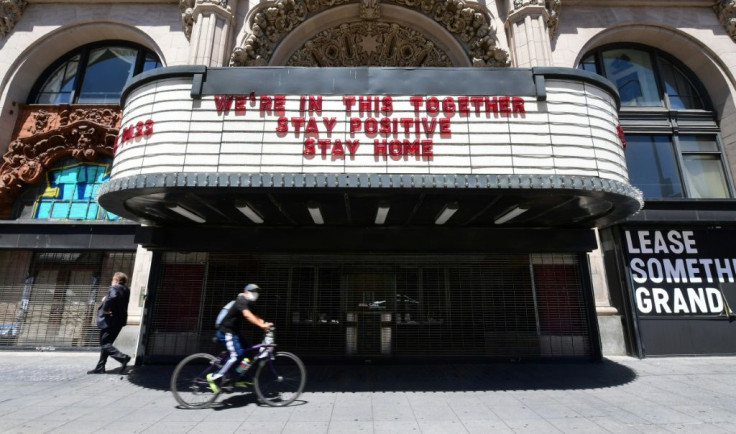 A Los Angeles cyclist in a face mask rides past the Million Dollar Theater, closed due to the coronavirus pandemic, with words on the marqee calling for togetherness