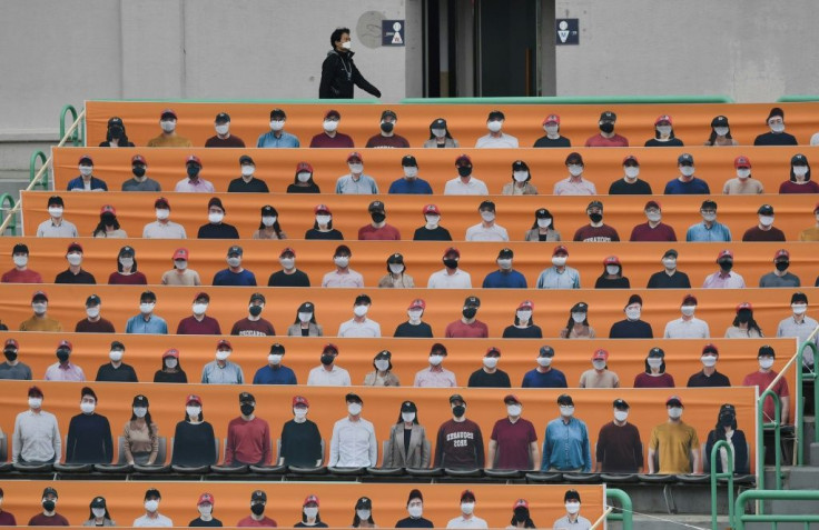 A man walks past banners depicting spectators in the stands prior to South Korea's new baseball season opening game between SK Wyverns and Hanwha Eagles in Incheon