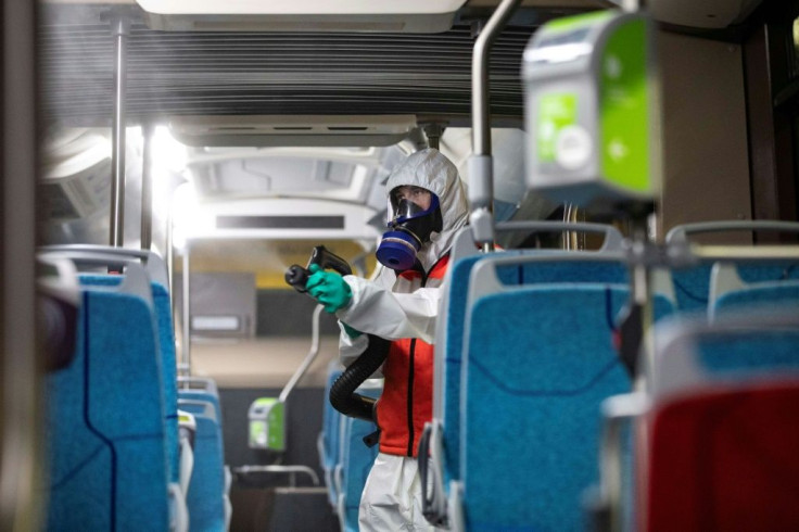 An employee of a cleaning company disinfects a bus on the outskirts of Paris
