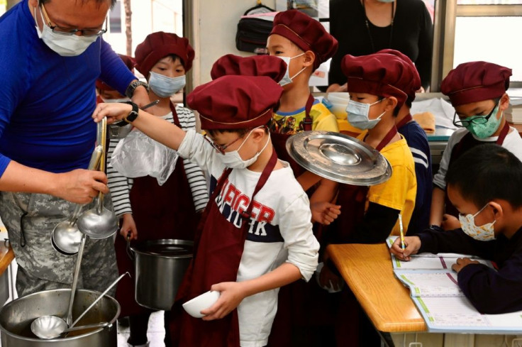 Students wearing face masks as a preventive measure to curb the spread of the COVID-19 coronavirus collect their lunch at an elementary school in Taipei in April 2020