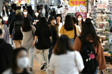 People wearing face masks walk through an underground shopping area in Seoul on May 6