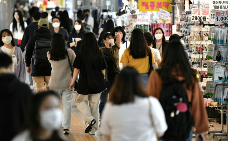 People wearing face masks walk through an underground shopping area in Seoul on May 6