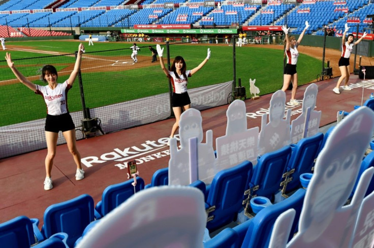 Cheerleaders are performing in front of cut-outs of fans