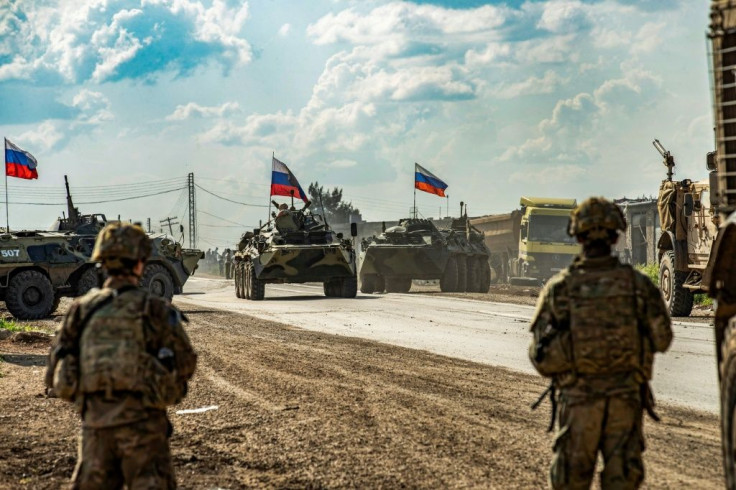 US soldiers stand along a road across from Russian military armored personnel carriers near the village of Tannuriyah in Syria's northeastern Hasakah province on May 2, 2020