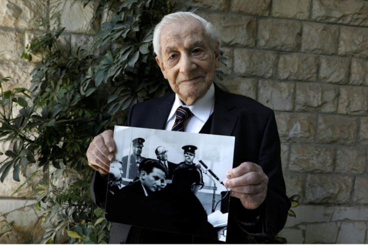 Bach, pictured holding a photograph showing himself (below) during the Eichmann trial, said, 'Not a day passes without me remembering some particular item, or some particular piece of evidence, or some particular moment from the Eichmann trial'