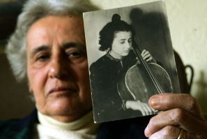 Holocaust survivor Anita Lasker-Wallfisch, pictured here in 2005, holds up a portrait of herself playing the cello in Berlin before World War II