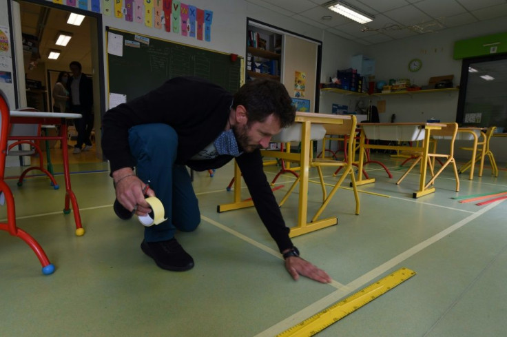 A teacher puts tape on the ground to mark safe distance areas for a classroom in Saint-Aubin-du-Cormier, western France, ahead of the gradual reopning of schools from May 11.