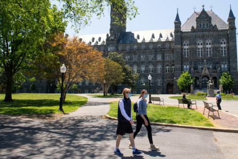 Two people wearing masks walk on the campus of Georgetown University in Washington