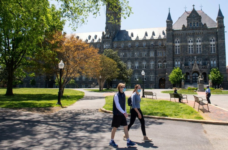 Two people wearing masks walk on the campus of Georgetown University in Washington