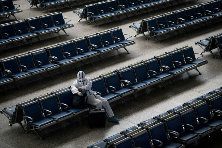 A passenger wears a hazmat suit as a precaution against the COVID-19 coronavirus as he waits for a train at Hankou Railway Station in Wuhan