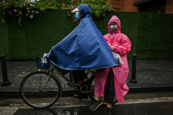 A couple wearing face masks ride a bicycle on a street in Wuhan