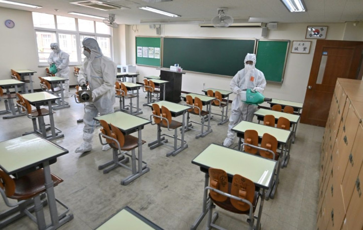 Health officials wearing protective gear spray disinfectant in a classroom at a high school in Seoul