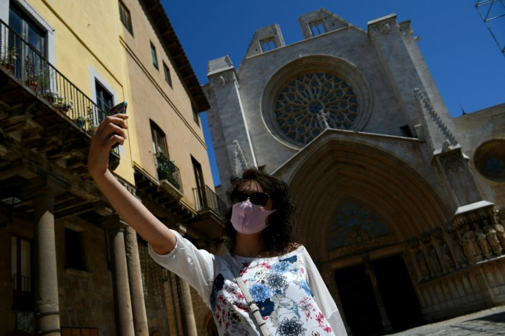 Venturing out, but with a mask, a woman takes a selfie outside Tarragona Cathedral as Spain, one of the countries worst hit by the coronavirus, looks to move gingerly back towards normal
