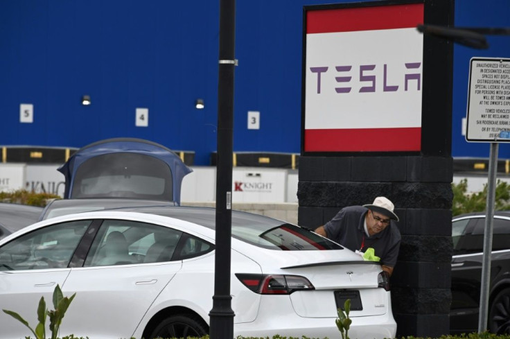 A Tesla employee cleans a car outside a Tesla showroom in Burbank, California, March 24, 2020