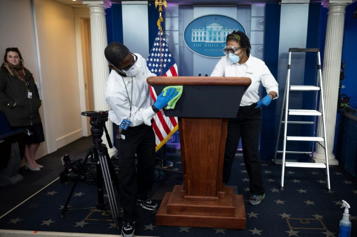 Cleaning staff disinfect the lectern in the White House Press Briefing Room