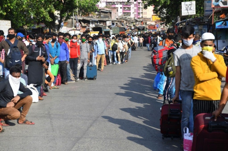 Migrant workers gather outside a Mumbai slum for a bus to take them to a railway station