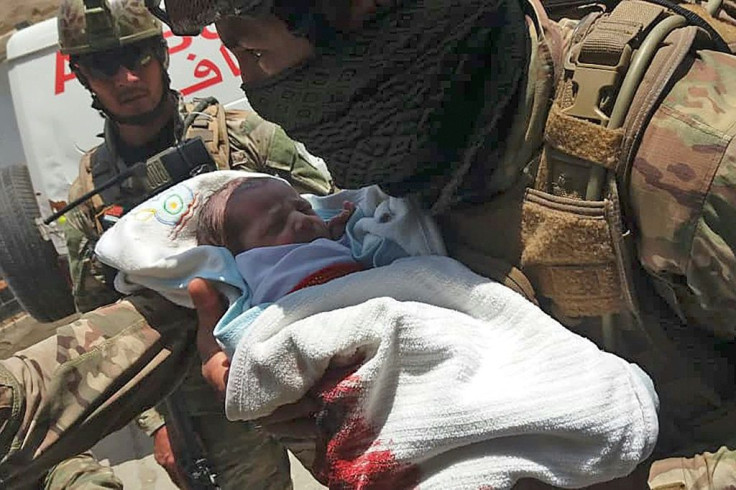 An Afghan security officer carries a newborn baby from a hospital after it is attacked in Kabul